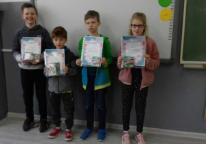 Zdjęcie przedstawia uczniów klasy 2c, trzymających dyplomy dla laureatów konkursu "Zimowy pejzaż"