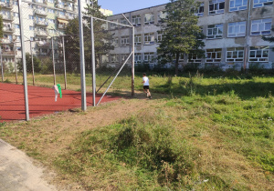 Uczeń pokonuje pierwszy zakręt na torze biegu. W tle budynek szkoły.