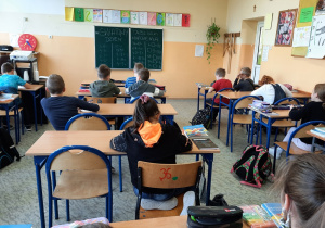 Widok z tyłu uczniów klasy 4b w pracowni matematycznej podczas pisania.