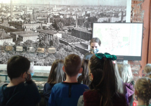 Uczniowie klasy 2a przed makietą Łodzi słuchają opowieści o historii miasta.