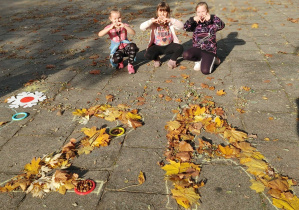 Trzy dziewczynki ułożyły Jesienny Totem z liści