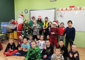 Grupa dzieci z Mikołajem i elfami w sali lekcyjnej