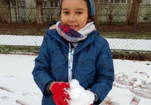 Chłopiec trzyma dużą kulę ulepioną ze śniegu